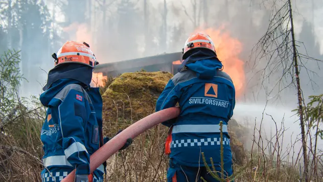 To personer slukker brann i en hytte i skogen