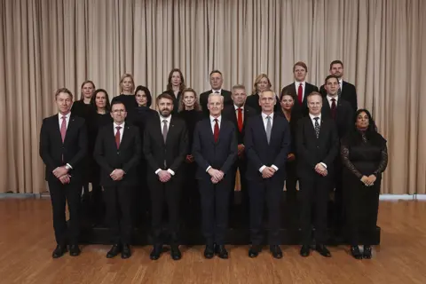 Gruppebilde av regjeringen på Sundvolden. Regjeringen står oppstilt på tre rader.