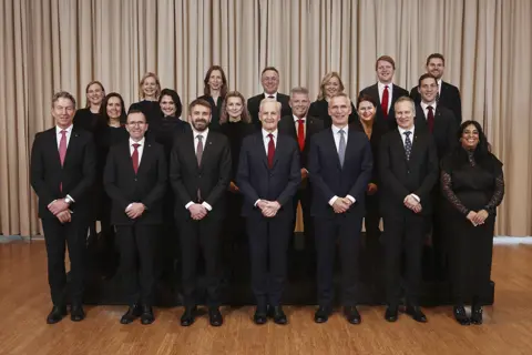 Gruppebilde av regjeringen på Sundvolden. Regjeringen står oppstilt på tre rader.